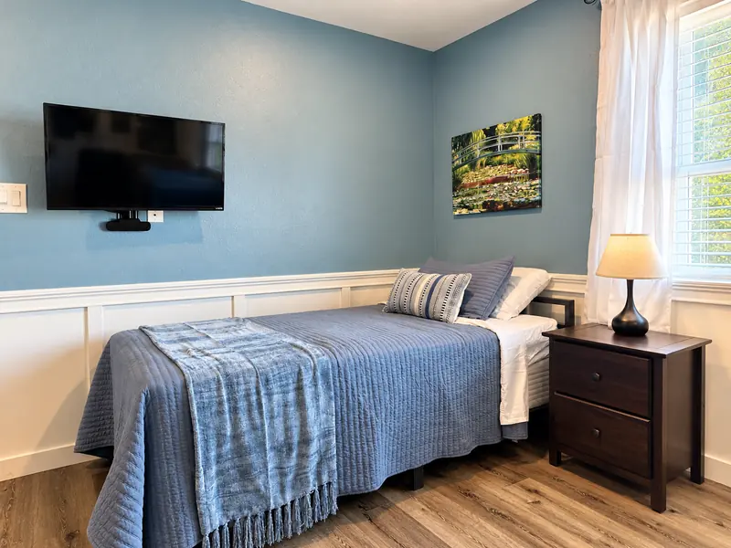 Bed with blue quilt, nightstand and lamp