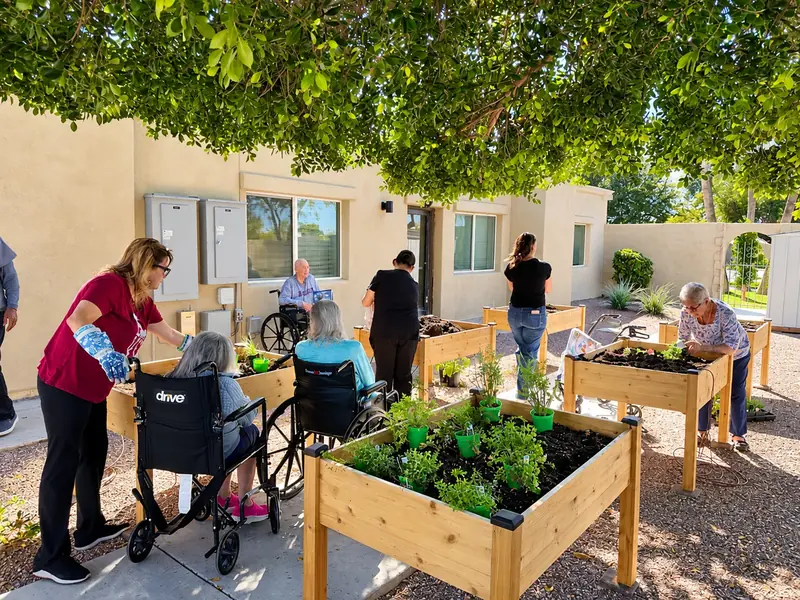 Residents and caregivers planting herbs in the raised garden beds
