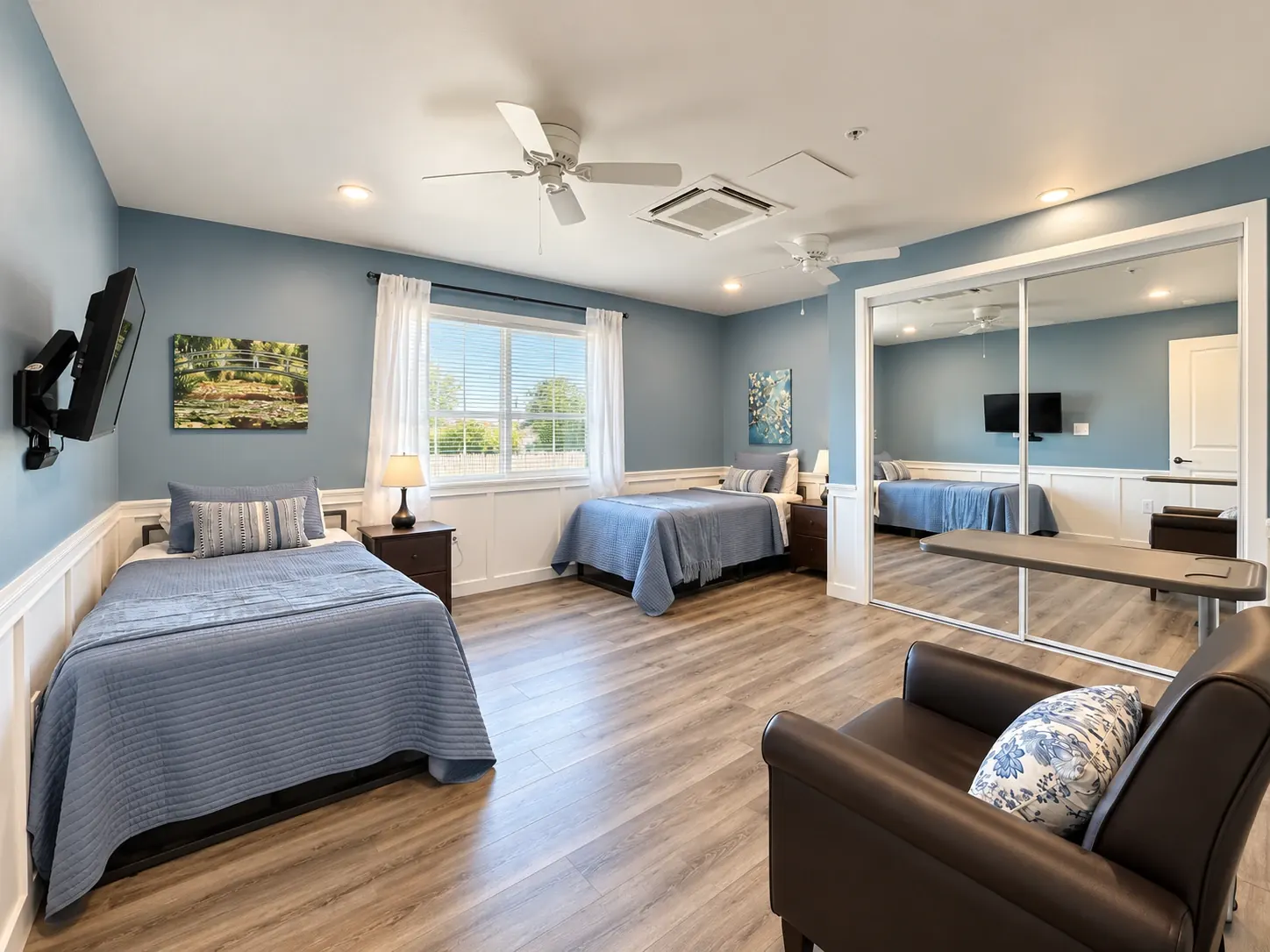 Renovated companionship room with two beds, art and a reading chair