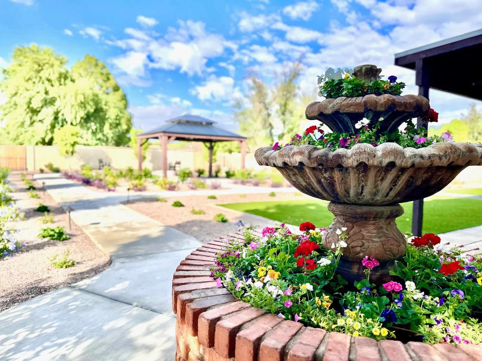 Tiered fountain full of flowers with the gazebo behind it