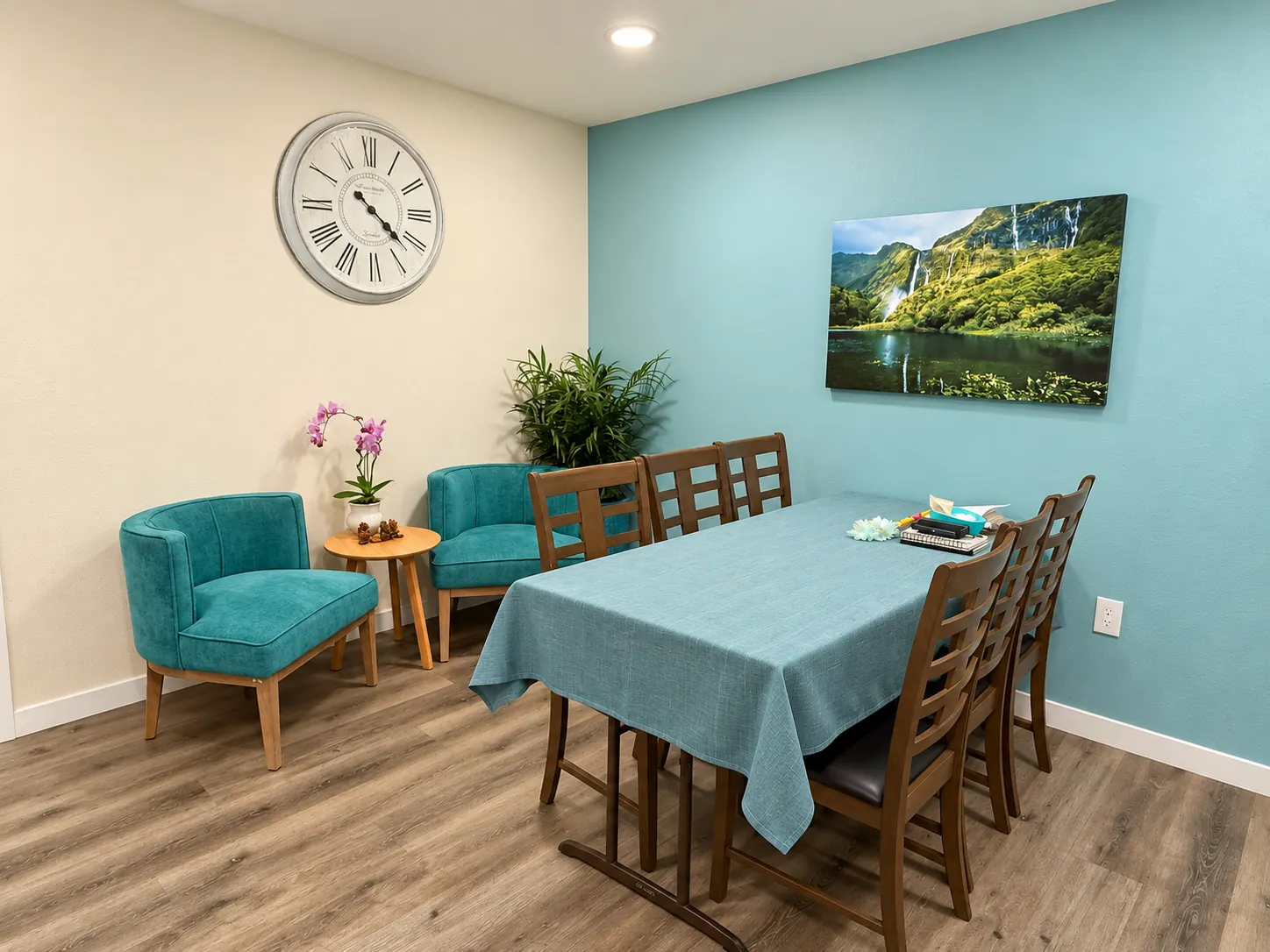 Family room with teal armchairs, a table for six and waterfall art